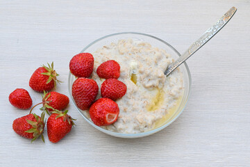 A plate of oatmeal porridge and ripe strawberries