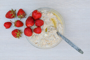 A plate of oatmeal porridge and ripe strawberries