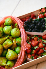 Box with strawberries, blackberries, figs lies on a tile