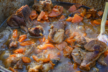 Sliced carrots and pieces of meat in a cauldron