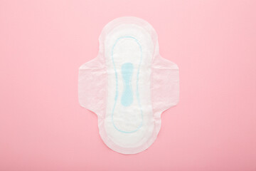New opened white sanitary towel on light pink table background. Pastel color. Closeup. Female...