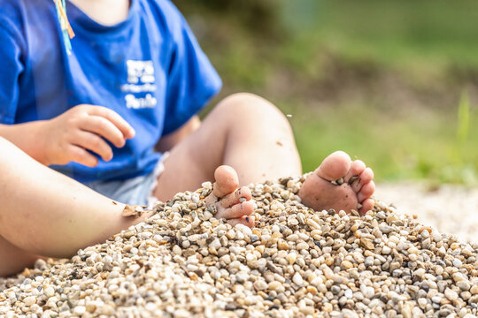 Close-up of the toes of a child playing with gravel. Playing children concept