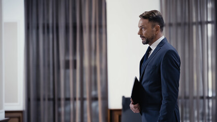 bearded businessman in formal wear holding paper folder