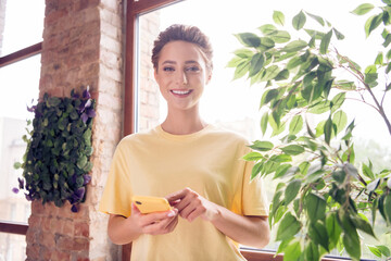 Photo of young charming attractive woman hold hand phone read message smile indoors inside house...