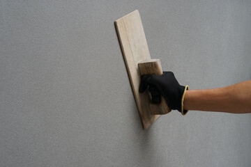 an old man hand holding wood trowel is plastering cement wall at home, concept a hobby in elderly...
