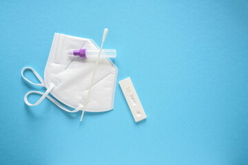 Covid-19 rapid test, utensils and a medical ffp2 face mask on a light blue background, concept for safety and health care during coronavirus pandemic, copy space, high angle view from above
