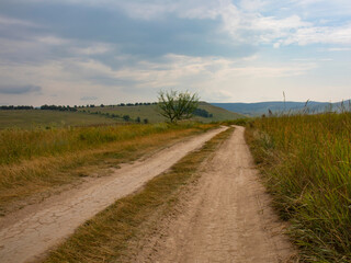 Fototapeta na wymiar A country road in the steppe on the hills.