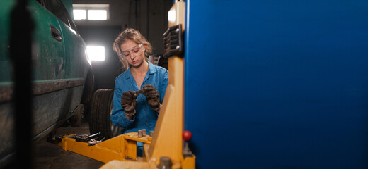 Fototapeta na wymiar Portrait of a woman auto mechanic in working overalls and glasses. Baner