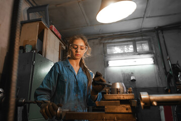 Fototapeta na wymiar young woman in her garage works on a lathe. Profession concept Turner, Metalworking, Turning, Industry, Metal.