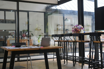 Office interior view with office desk, wooden table, chair, laptop, documents and stationary.