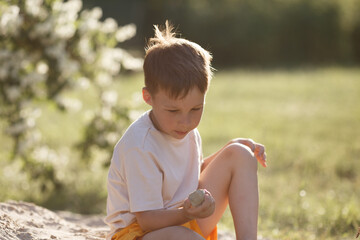 the boy plays with a sandstone, holds it in his hand and examines it