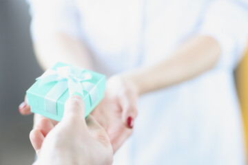 Man giving woman blue gift box with bow closeup