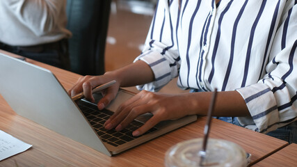 Closed up and cropped with businesswoman hand working with notebook on wooden table in the meeting room and sitting beside colleague.