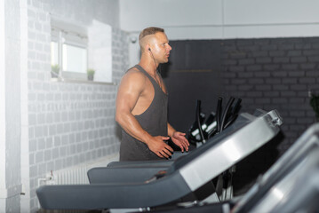 Fototapeta na wymiar Young man in sportswear running on treadmill at gym.Handsome sport gym man running on the treadmill.Indoors shot.