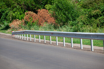 red road reflectors along the road. metal road fencing of barrier type, close-up. Road and traffic safety. reflective paint on sign. Median barrier
