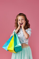 cute little caucasian child girl holds shopping bags