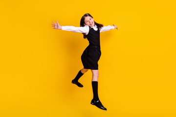 Fototapeta na wymiar Full length body size photo schoolgirl in uniform jumping high overjoyed isolated vivid yellow color background