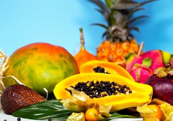 Papaya, Dragon Fruit, Mango, Mangosteen, Winter Cherry, Granadilla, Salak and Pineapple. Fresh Tropical Fruits. On blue background. Top view. Fruit Background