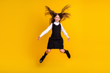 Fototapeta na wymiar Full length body size photo schoolgirl in uniform jumping up with flying hair isolated vivid yellow color background