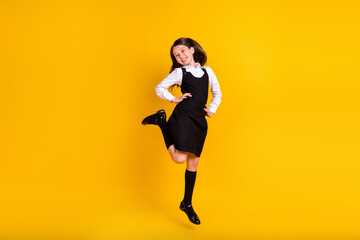 Fototapeta na wymiar Full length body size photo little schoolgirl jumping up laughing happy isolated vivid yellow color background