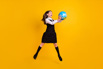 Full body photo of small happy amazed cute girl jump up hold globe subject isolated on yellow color background