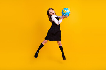 Full length body size photo schoolgirl amazed jumping with globe on geography isolated vivid yellow color background