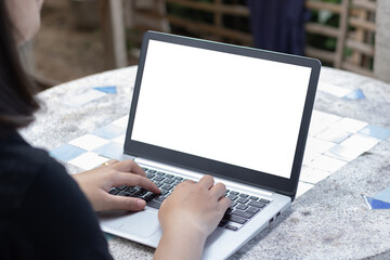 Woman using or typing laptop outside cafe restaurant with natural. Laptop computer on white desk and white blank on screen.