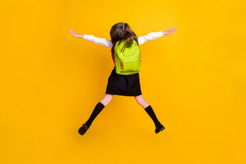 Fototapeta na wymiar Back rear spine side view photo of small schoolgirl jump up wear backpacki solated on yellow color background