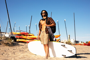 Portrait of handsome surfer with his surfboard. Young man preparing for the surf