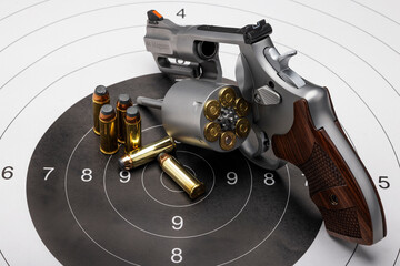 Revolver hand gun with bullets on bull eye target paper background