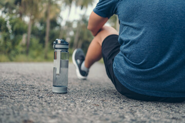 water bottle on the ground side.sport man sitting after running. Sport thirsty and resting after exercise.