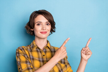 Photo of adviser girl indicate forefinger empty space promote sale wear plaid shirt isolated blue...
