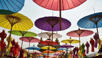 Fototapeta na wymiar Colorful paper umbrellas were hung to decorate the corridor from the temple gate against the sky background.