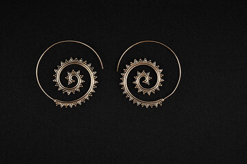 A pair of earrings kept on a plain black background.