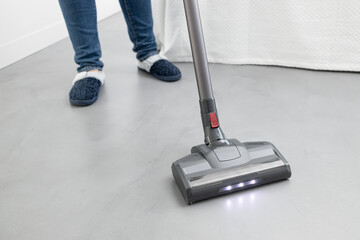 Woman cleaning with a cordless vacuum cleaner in a modern bedroom. Copy space