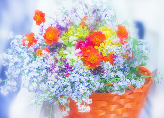 Multi-colored bouquet of summer flowers in orange basket