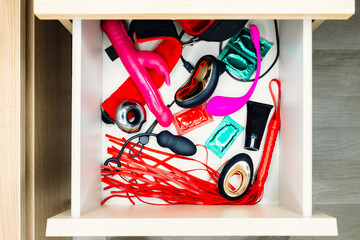 Bedside wooden table or nightstand drawer full of sex toys