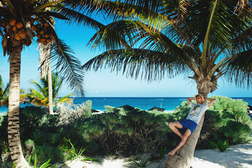 Attractive young tourist man relaxing on palm tree on the caribbean beach. Lazy time, summer vacation concept