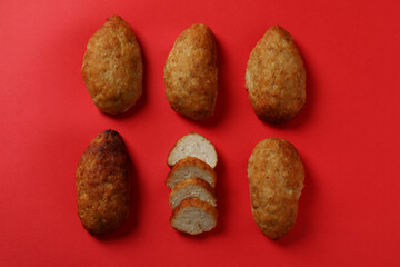 Tasty cutlets on red background, top view