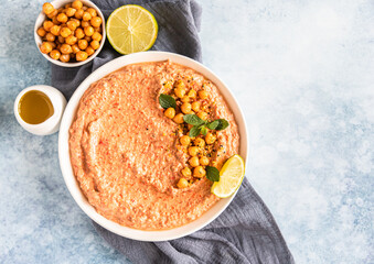 Roasted red pepper hummus garnish with mint and lime. Mashed chickpeas with red bell pepper, lime and mint. Vegetarian snack. Top view.