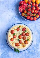 Savoury cheesecake with tomatoes decorated with mint, blue concrete background. Top view.