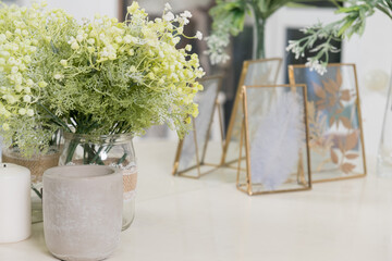 Decorative flowers, candles and dried plants in a frame on the dressing table. Close-up of bedroom or bathroom interior details. Selective focus.