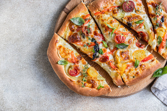Pinsa with vegetables and cheese, concrete background. Traditional rome pizza. Top view.