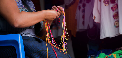 Craftswoman hand weaving blouses, woman's hands knitting by hand, with colorful threads