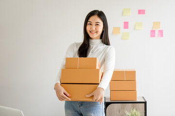 Starting Small business entrepreneur SME freelance,Portrait young woman working at home office, BOX,smartphone,laptop, online, marketing, packaging, delivery, SME, e-commerce concept