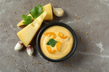 Bowl of cheese sauce and ingredients on gray textured table