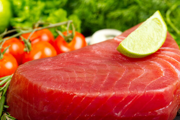 Raw tuna fillet steak with dill, lemon and spices in olive cutting board, ready for cooking