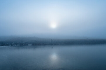 Fototapeta na wymiar A man standing in foggy near the lake in the morning