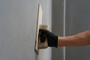 hand of worker plastering cement wall at construction site with copy space, selective focus
