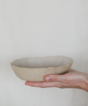 Hands holding ceramic bowl isolated on white background. Handmade ceramic tableware and pottery